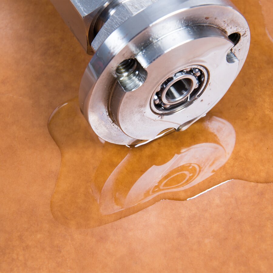 Metallteil auf Ölpapier mit Wasserpfütze